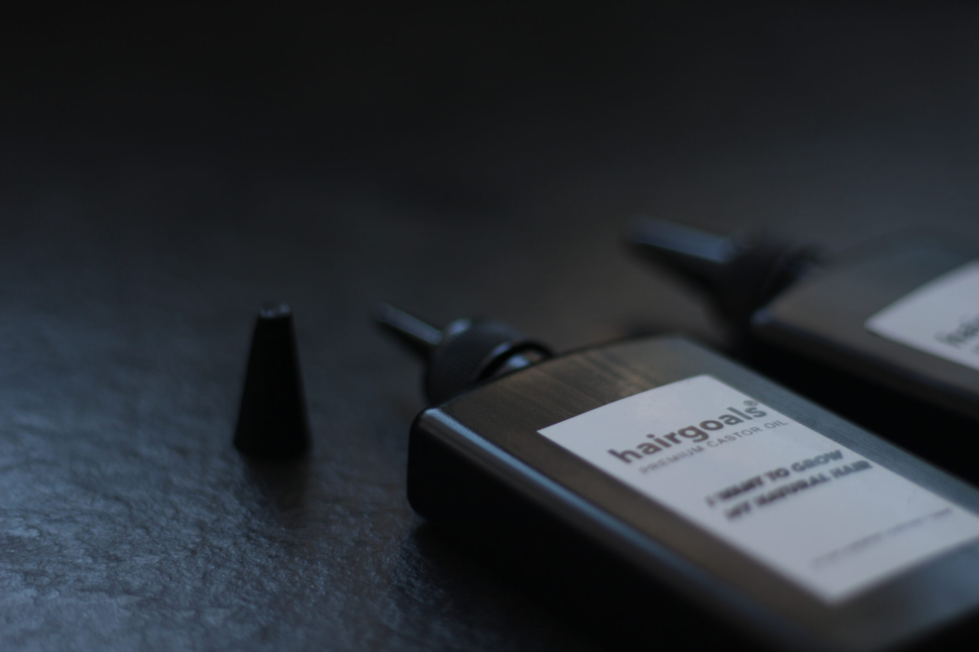 Close-up of a hairgoals premium castor oil bottle on a dark slate surface