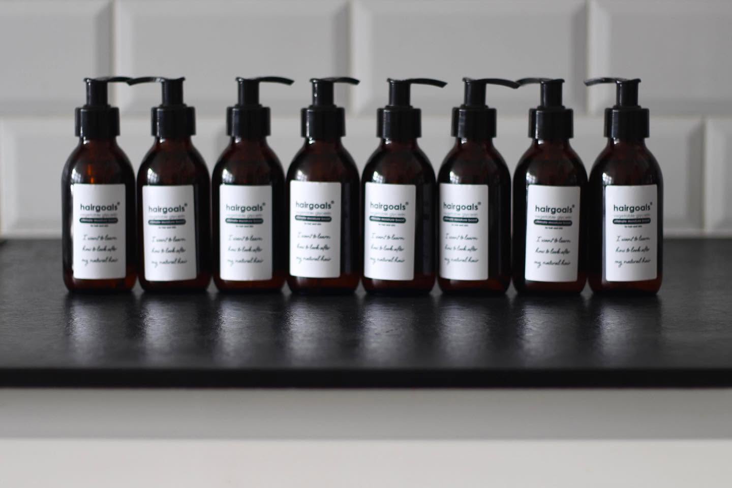 A row of hairgoals vegetable glycerin pump bottles on a black shelf