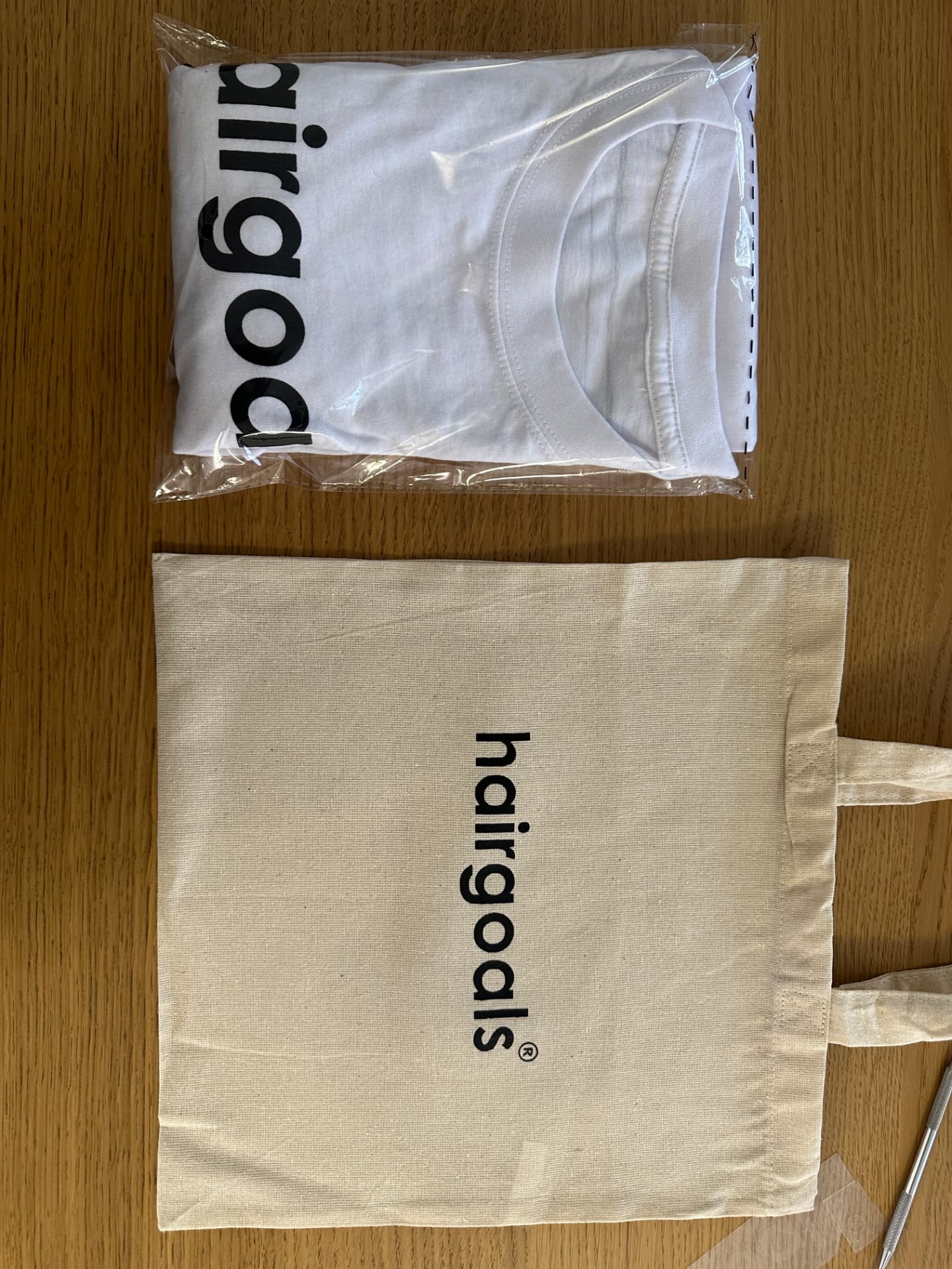 hairgoals length check t-shirt in retail packaging beside a hairgoals canvas tote bag